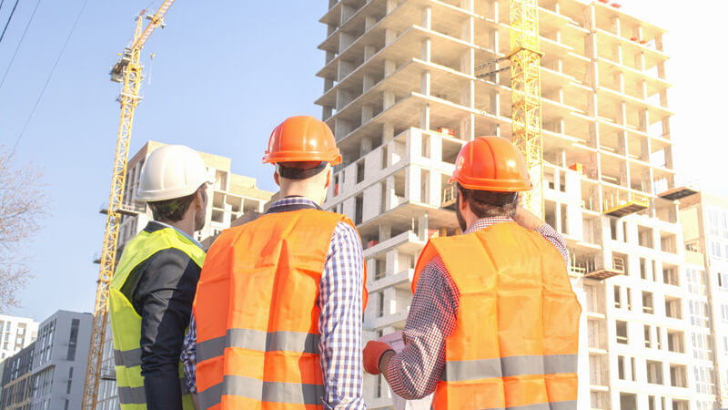 Construction workers standing in front of tall buildings.