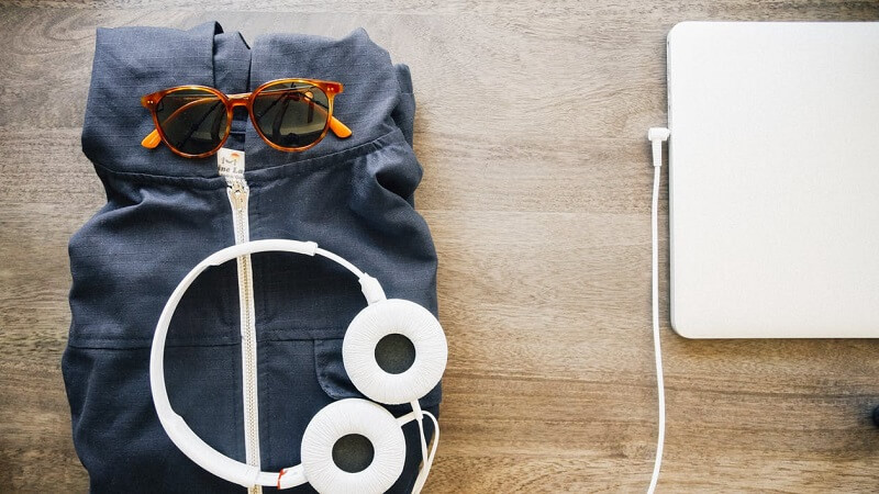 Image of sweatshirt, sunglasses, laptop and headphones.