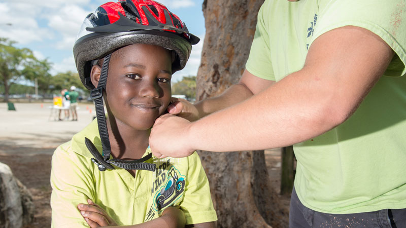 young boy receiving helmet assistance from an adult
